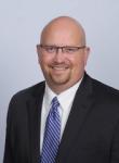 Charlie Clark, a man wearing glasses in a suit with a striped, blue tie