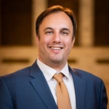 photo of Geoff wearing a blue suit and gold patterned tie