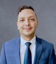 Photo of Kenneth wearing a blue suit, white shirt, and blue tie