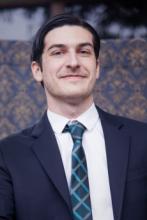 Photo of Nathan Olsen wearing a suit and Green patterned tie